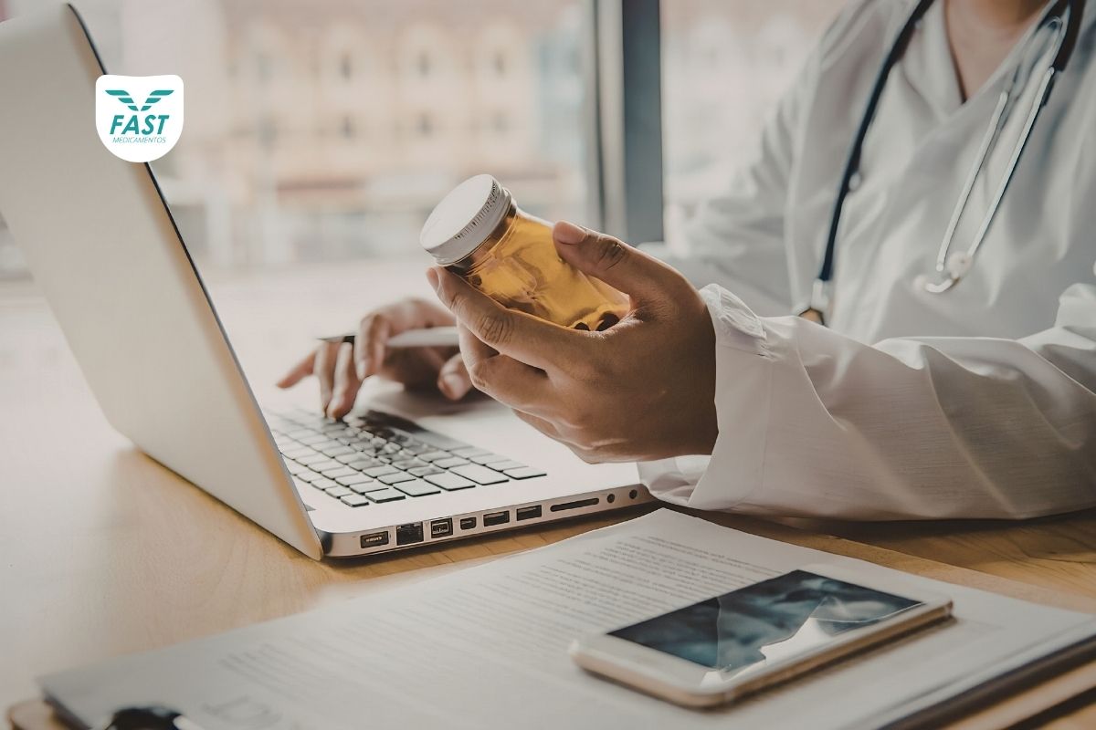 Médica segurando remédio de alto custo e mexendo em notebook